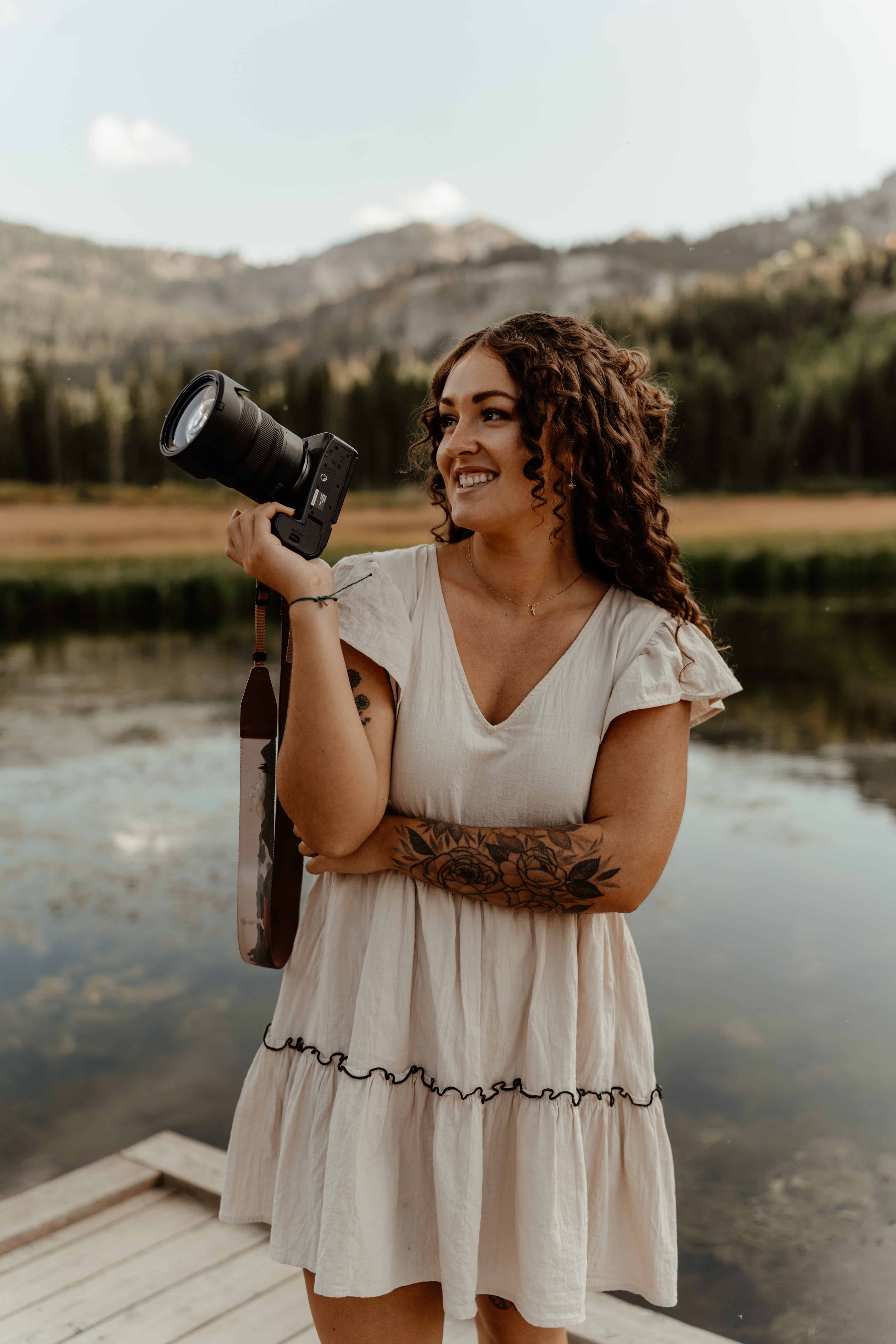utah elopement photographer looking at camera and smiling in front of lake and mountains 